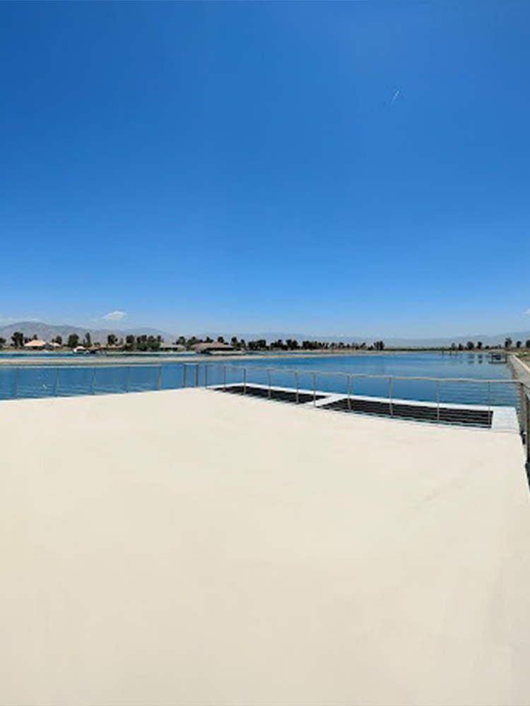 Three construction workers applying bright light blue waterproof coating on outdoor deck